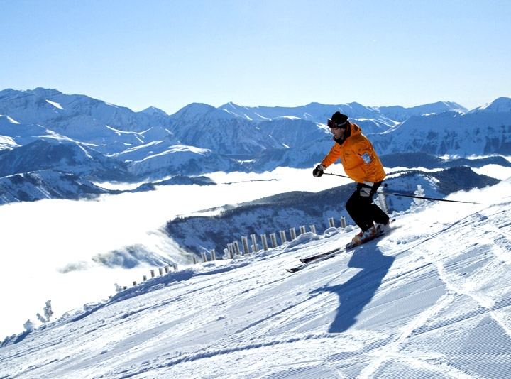 Skieur sur une piste ensoleillée, face aux sommets enneigés